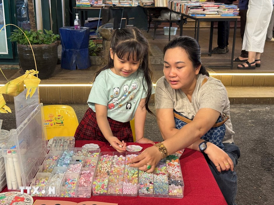 Phụ huynh đưa em nhỏ tới Ng&agrave;y hội để tham gia workshop l&agrave;m v&ograve;ng tay. (Ảnh: TTXVN)