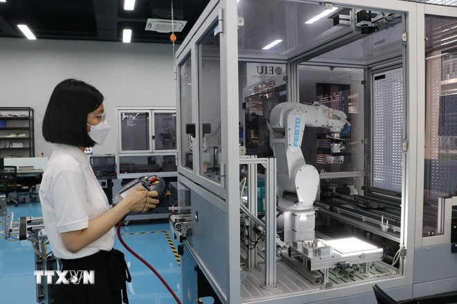 Vận hành robot tự động hóa trong sản xuất trong nhà máy để nâng cao năng suất lao động. (Ảnh: TTXVN)