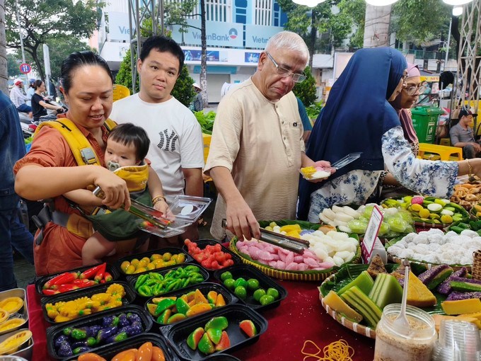 Du khách trong nước và quốc tế tìm hiểu, chọn mua bánh dân gian Nam bộ tại chợ Bình Tây. (Ảnh: SGGP)