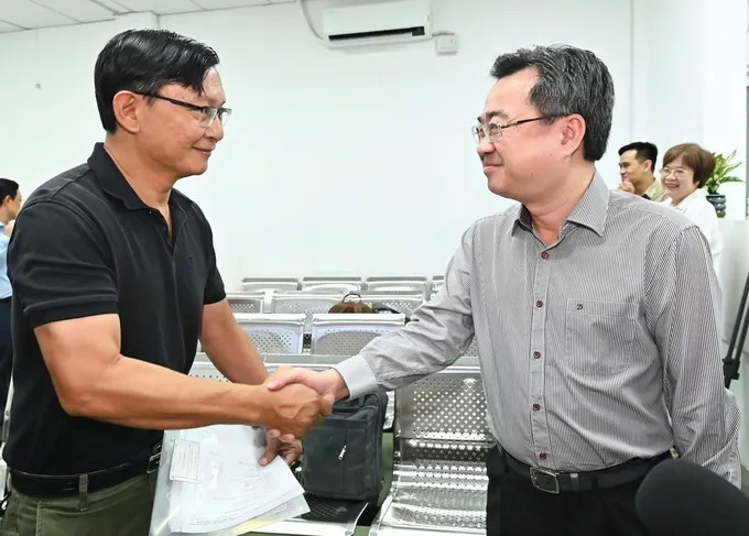 Đồng chí Nguyễn Thanh Nghị trò chuyện với người dân đến thực hiện thủ tục hành chính. (Ảnh: SGGP)