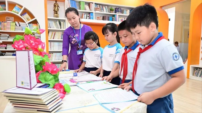 Cô và trò Trường Tiểu học Trần Hưng Đạo (phường Cầu Ông Lãnh, TPHCM) bên mô hình “Không gian văn hóa Hồ Chí Minh” ngay trong khuôn viên thư viện nhà trường (Ảnh: Văn Minh)