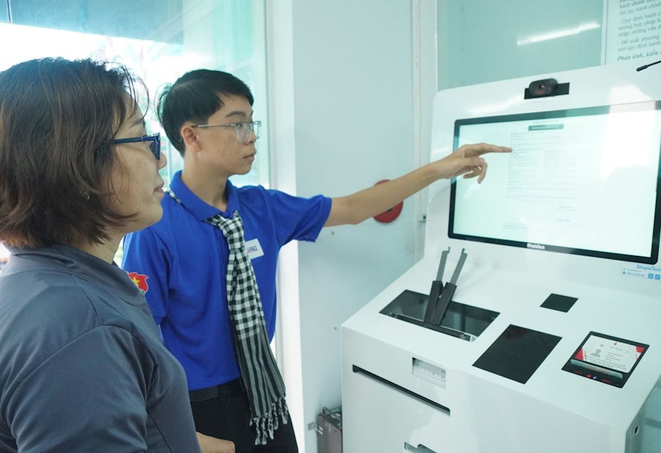 Cô Nguyễn Thị Hồng được hướng dẫn thực hiện các thủ tục hành chính công thông qua hệ thống hỗ trợ từ trợ lý ảo.