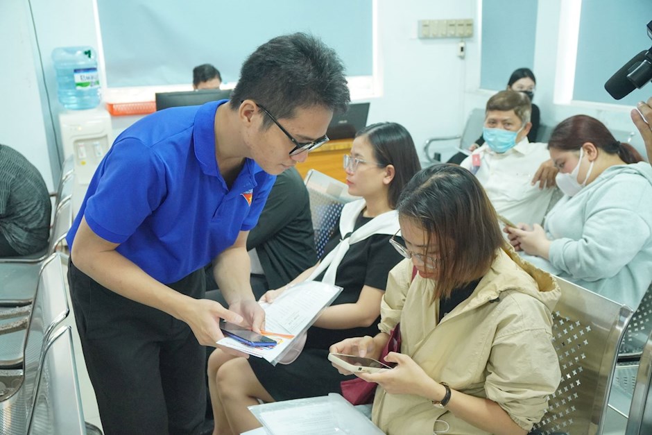 Các đoàn viên thanh niên phường Tân Hưng hướng dẫn người dân quét mã QR để thực hiện thao tác theo hướng dẫn Chatbot "Hỏi - đáp phường Tân Hưng" khi thực hiện các thủ tục hành chính.