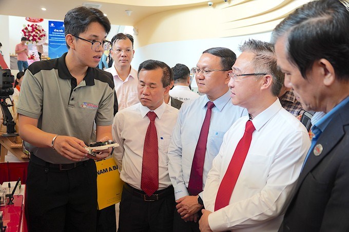 Đồng ch&iacute; Đặng Minh Th&ocirc;ng (thứ 2 từ phải sang) nghe đại diện Trường Đại học Kỹ thuật c&ocirc;ng nghệ giới thiệu về chip thiết kế vi mạch do trường nghi&ecirc;n cứu, s&aacute;ng chế. (Ảnh: SGGP)