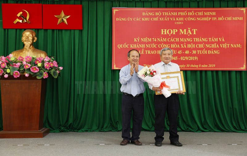Thành ủy viên, Trưởng Ban Quản lý các Khu Chế xuất và Khu Công nghiệp TP Nguyễn Hoàng Năng trao Huy hiệu 40 năm tuổi Đảng cho đảng viên. (Ảnh: Minh Trí)
