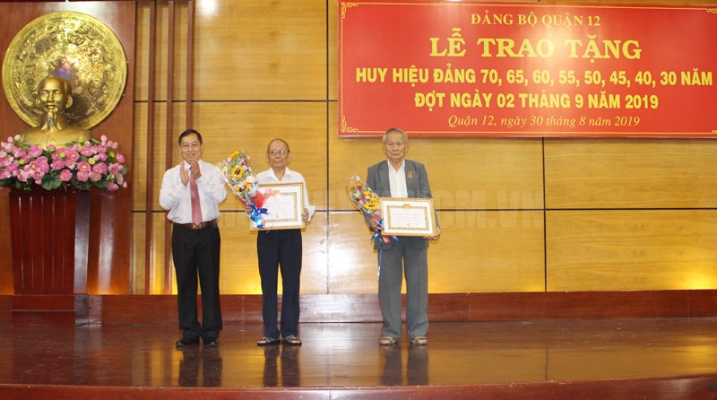 Đồng chí Trần Hữu Trí, Bí thư Quận ủy, Chủ tịch HĐND Quận 12 trao Huy hiệu Đảng cho đảng viên 70 năm tuổi Đảng. (Ảnh: Đoàn Nam)