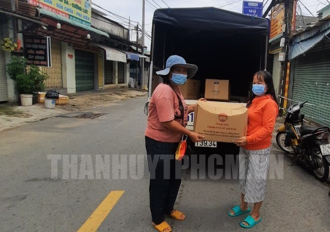 Cô Trần Thị Thu Tâm (bìa trái) tặng quà cho người dân khu phố 1 có hoàn cảnh khó khăn do dịch Covid-19