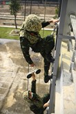 Đồng đội hỗ trợ nhau leo tường kính.